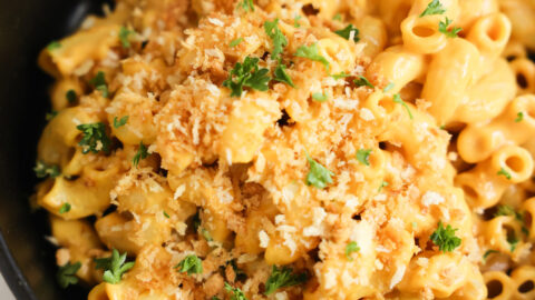 A close-up shot of vegan butternut squash mac and cheese in a black bowl with panko breadcrumbs.