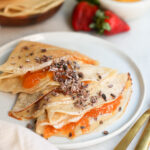 vegan crepes on a plate surrounded by fruit
