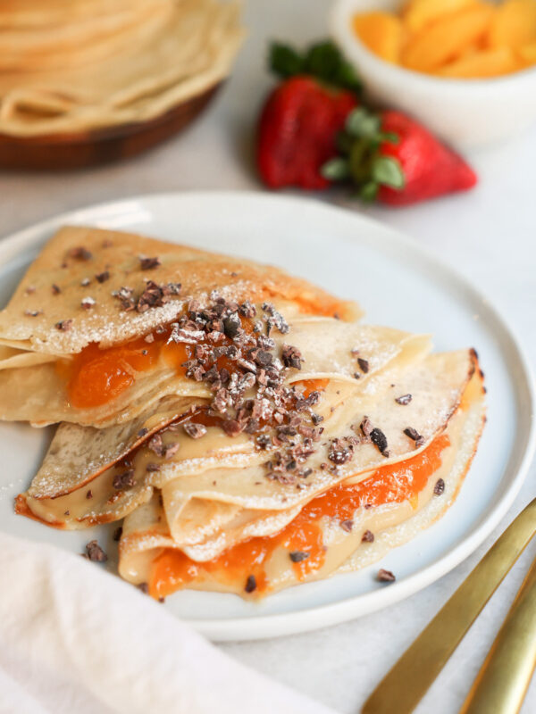 vegan crepes on a plate surrounded by fruit