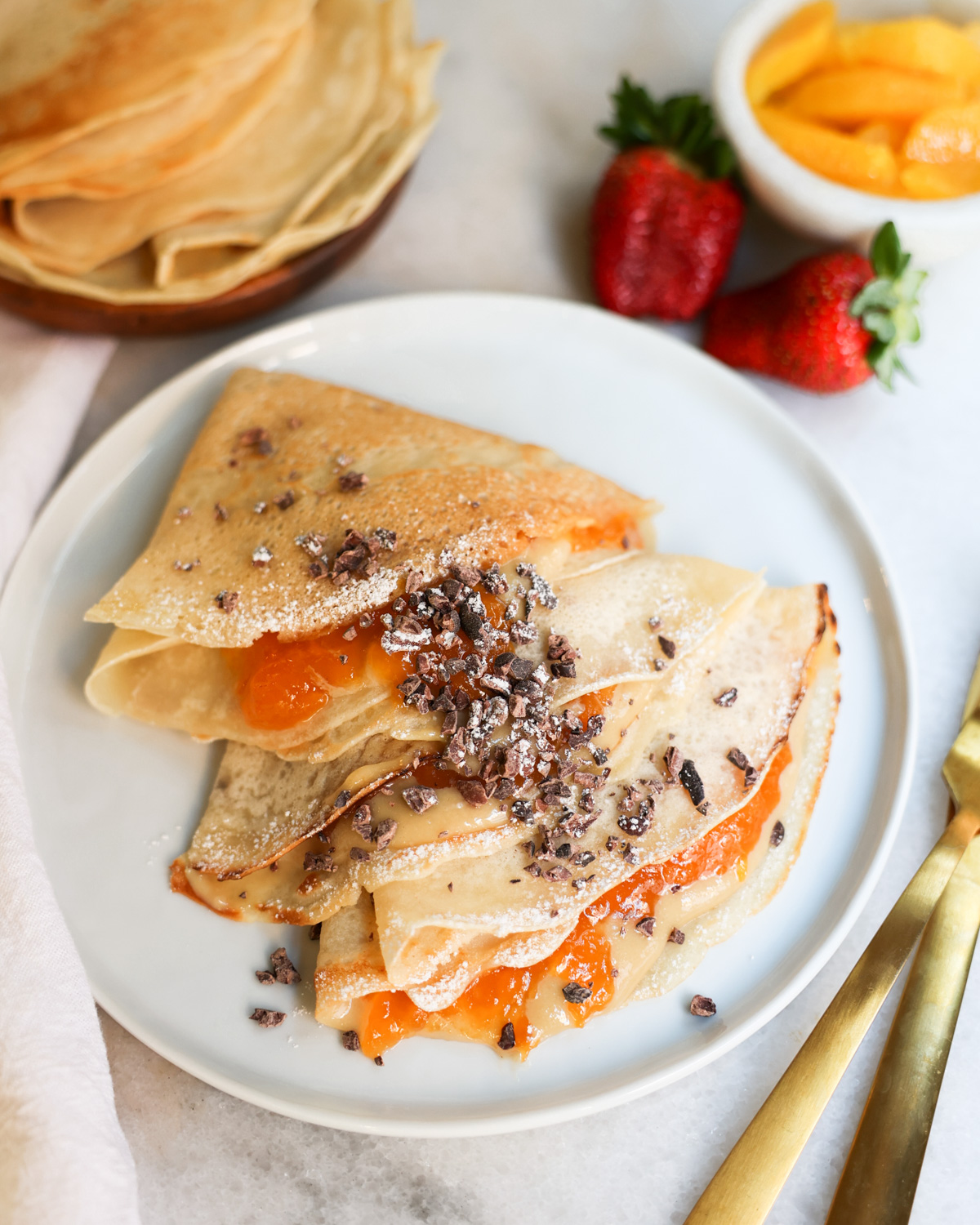 overhead of vegan crepes on a plate with peach jam