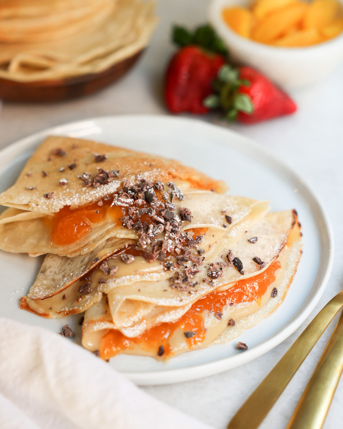 vegan crepes on a plate surrounded by fruit