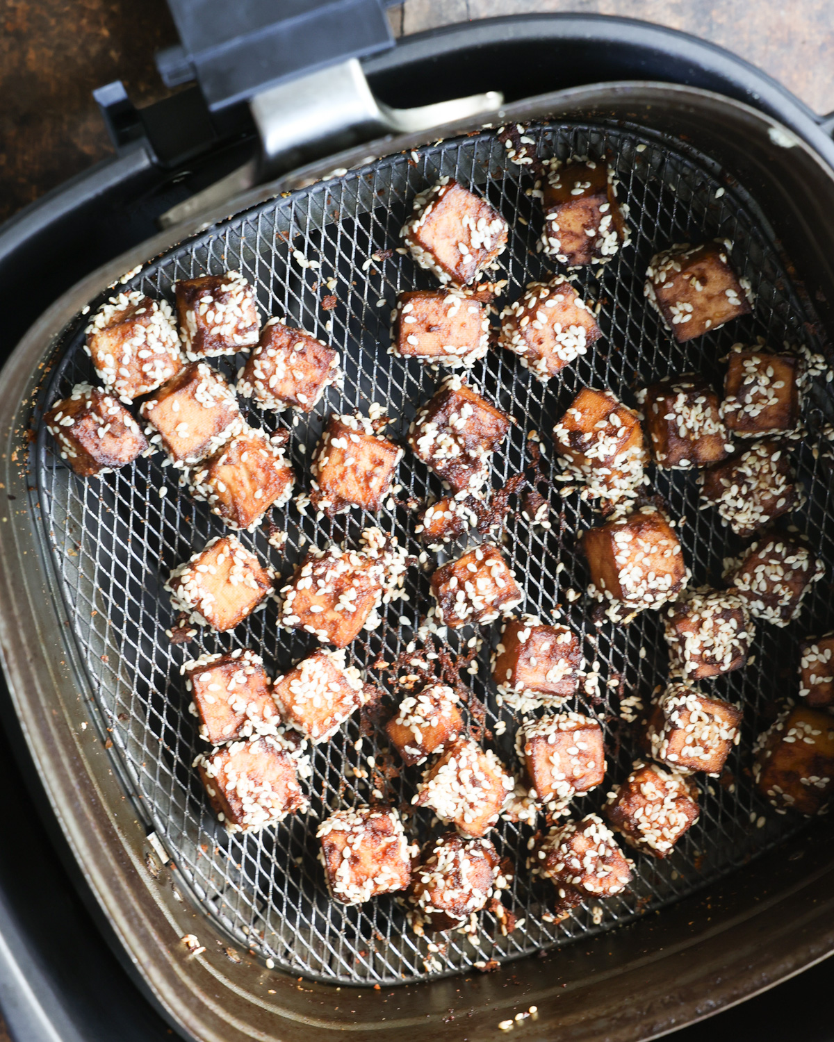 Cooking the air fryer tofu cubes in the air fryer basket.