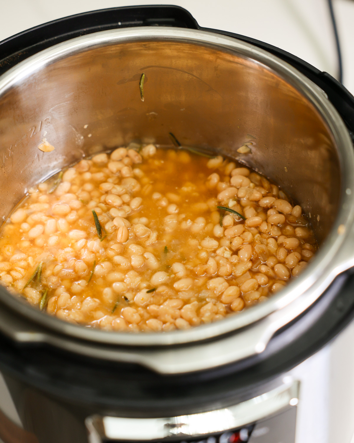 An angled shot of the Instant Pot white beans with lemon and rosemary in the Instant Pot.