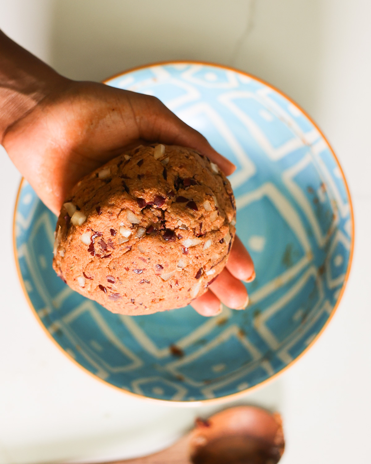 A hand holding a ball of vegan sausage dough before shaping.