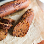 A close-up shot of cooked vegan sausage on crinkled parchment paper.