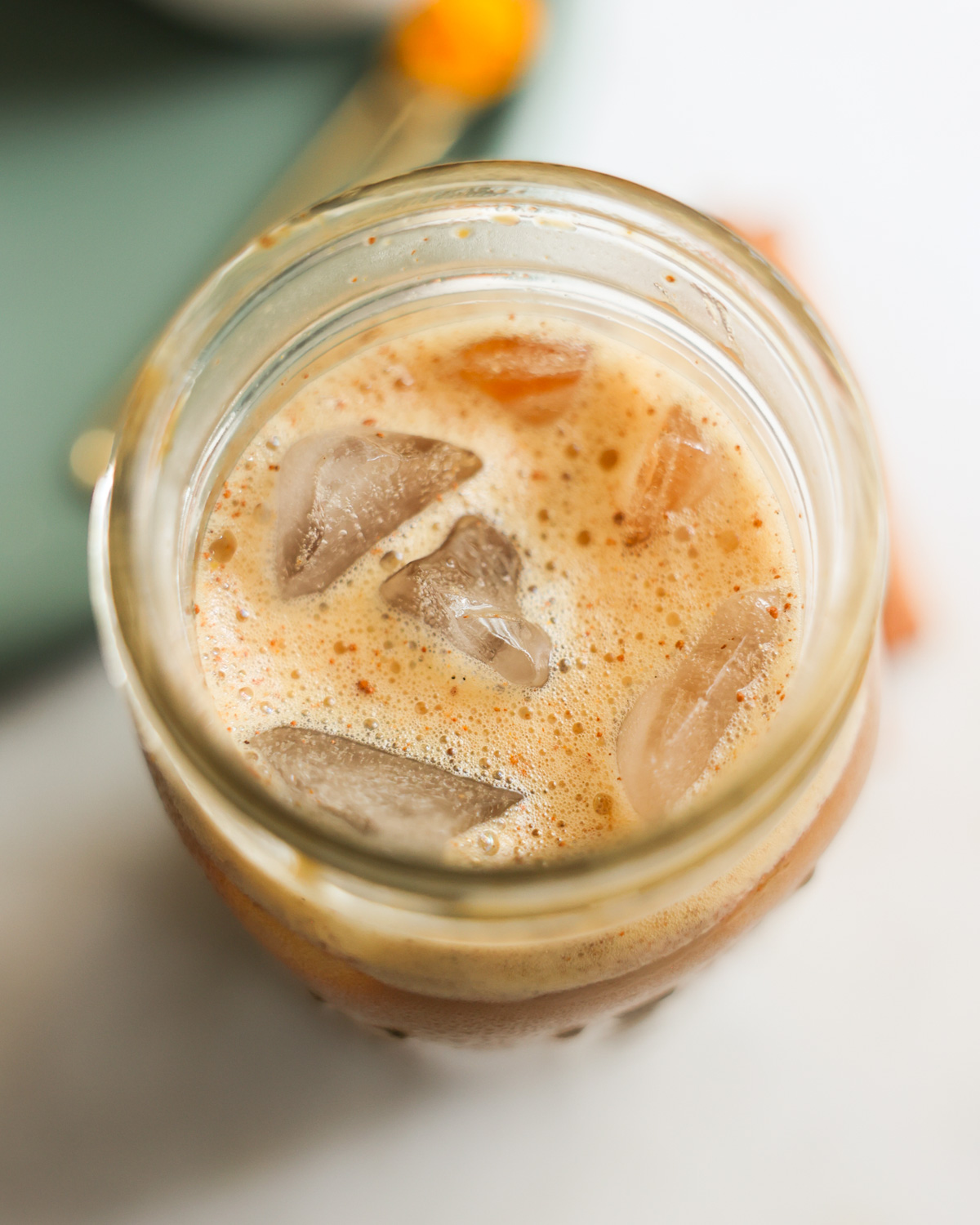 overhead of foamy oat milk iced latte in jar