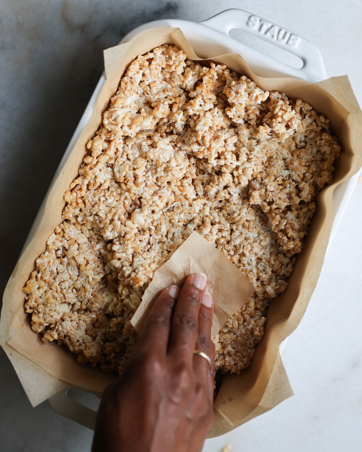 overhead of brown hand pressing down Vegan Rice Krispy Treats batter