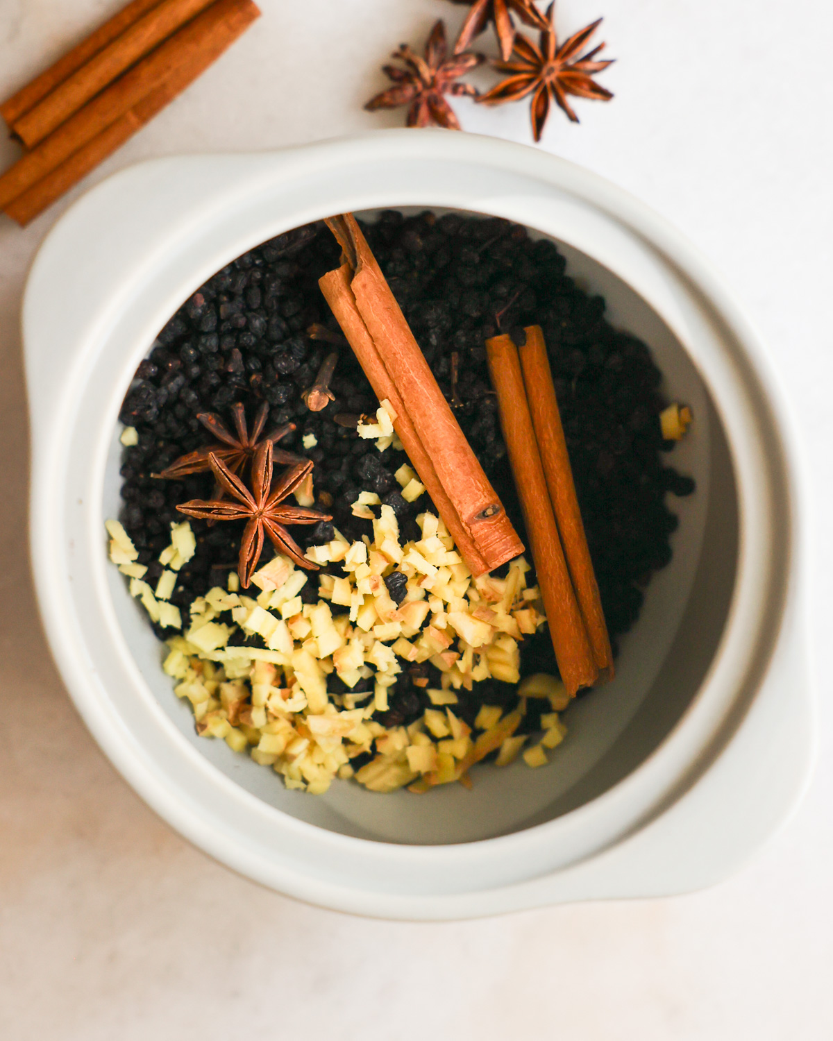 An overhead shot of a crock of dried elderberries with spices.