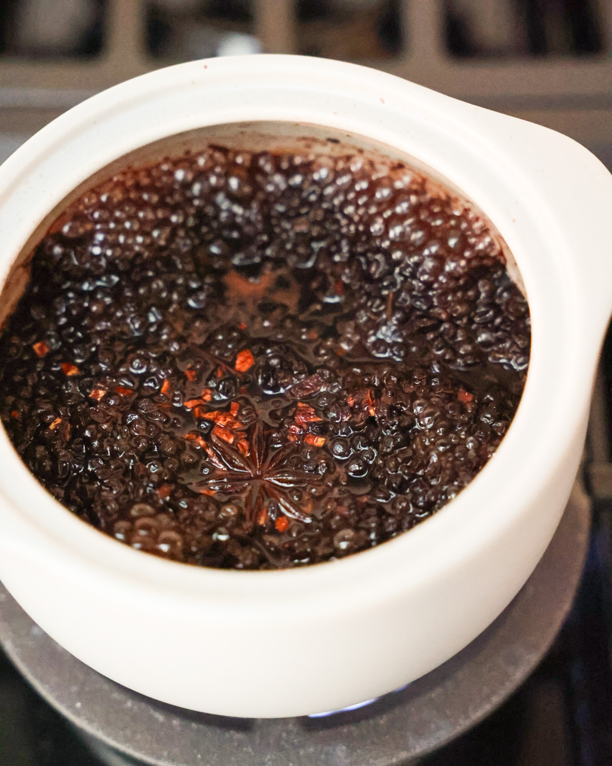 An up-close side shot of the elderberries simmering in water with spices.