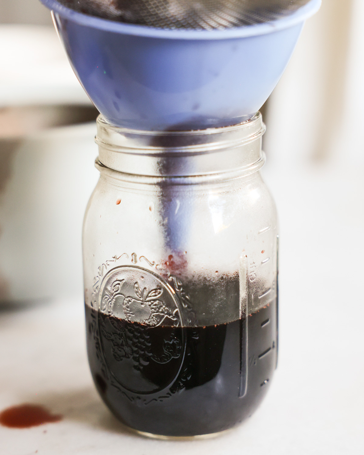 Funneling the elderberry syrup into a glass jar.