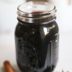 An up-close shot of a small jar of elderberry syrup.