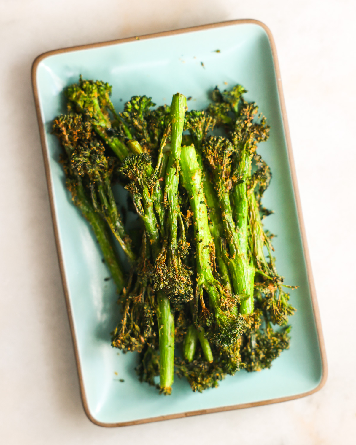 Air fryer broccolini on a small serving plate.