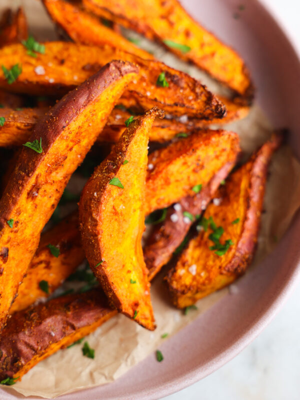 close up of sweet potato wedges on a pink plate