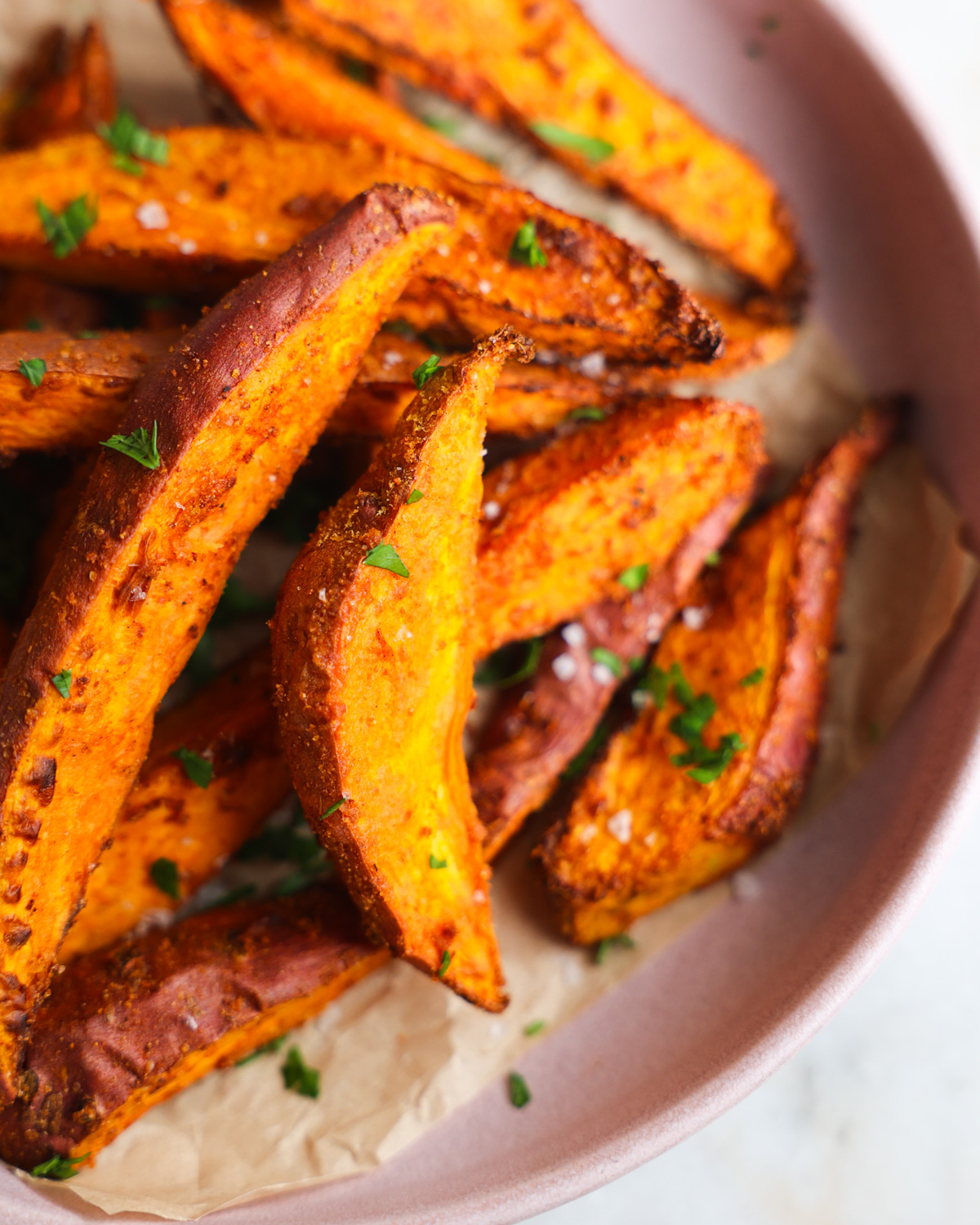 close up of sweet potato wedges on a pink plate