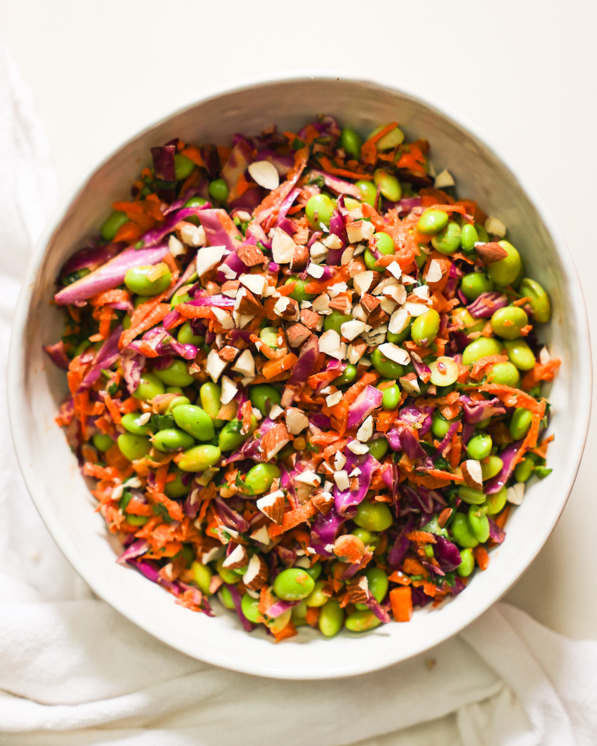 An overhead shot of a bowl of edamame salad garnished with chopped almonds.