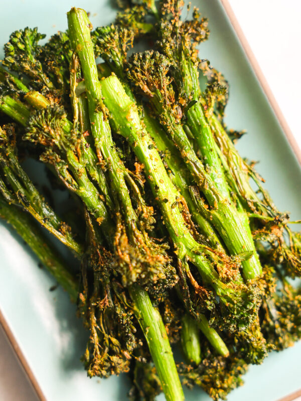 A close-up shot of the air fryer broccolini on a green plate.