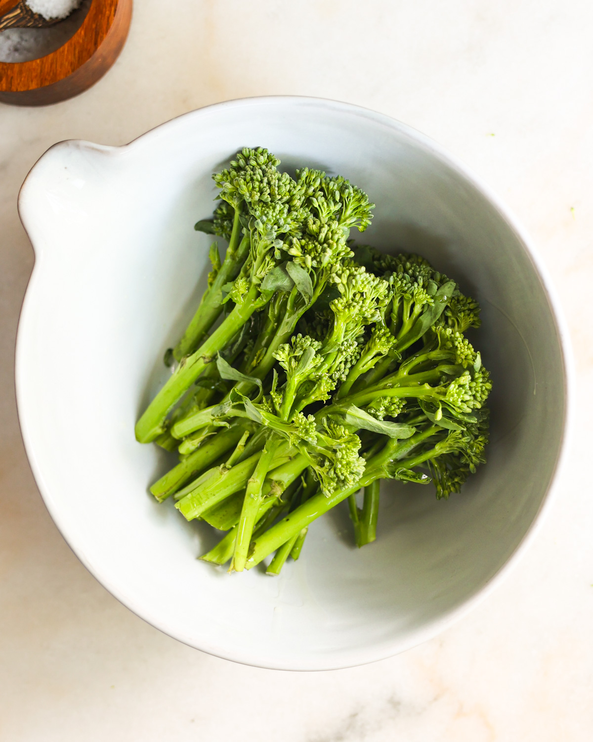 An overhead shot of the air fryer broccolini in a white mixing bowl.