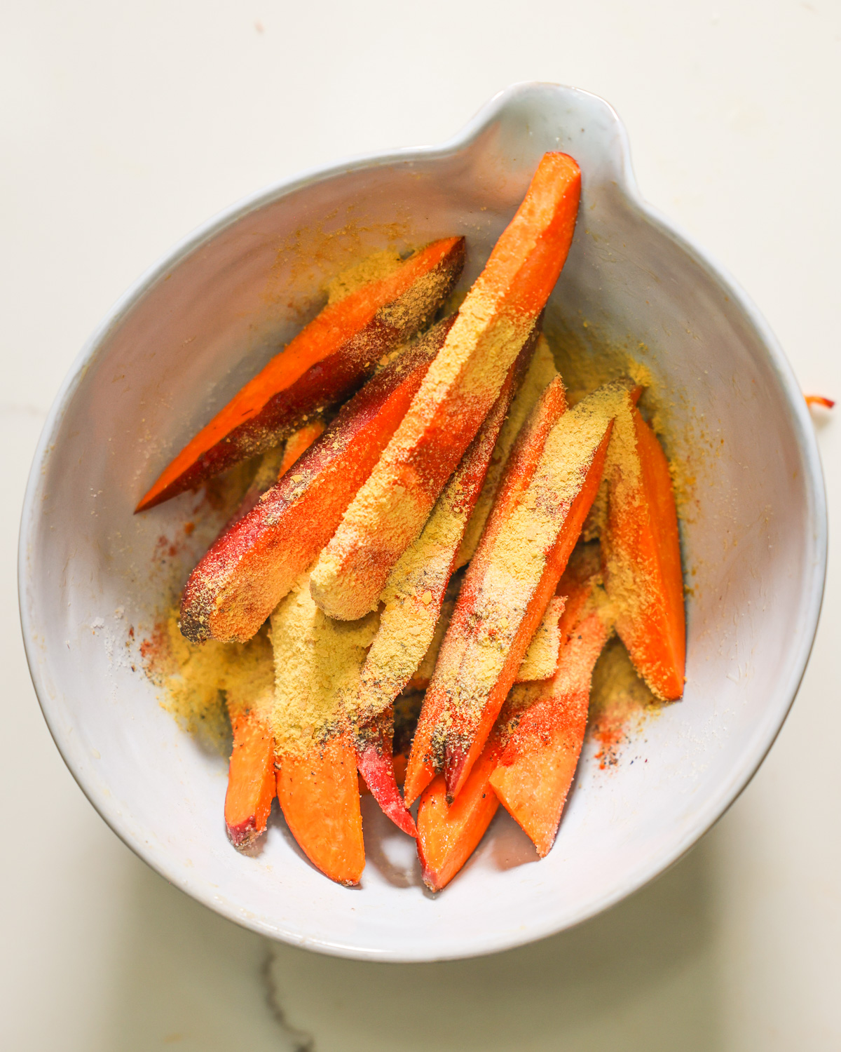 overhead of sweet potato wedges in a bowl coated with spices