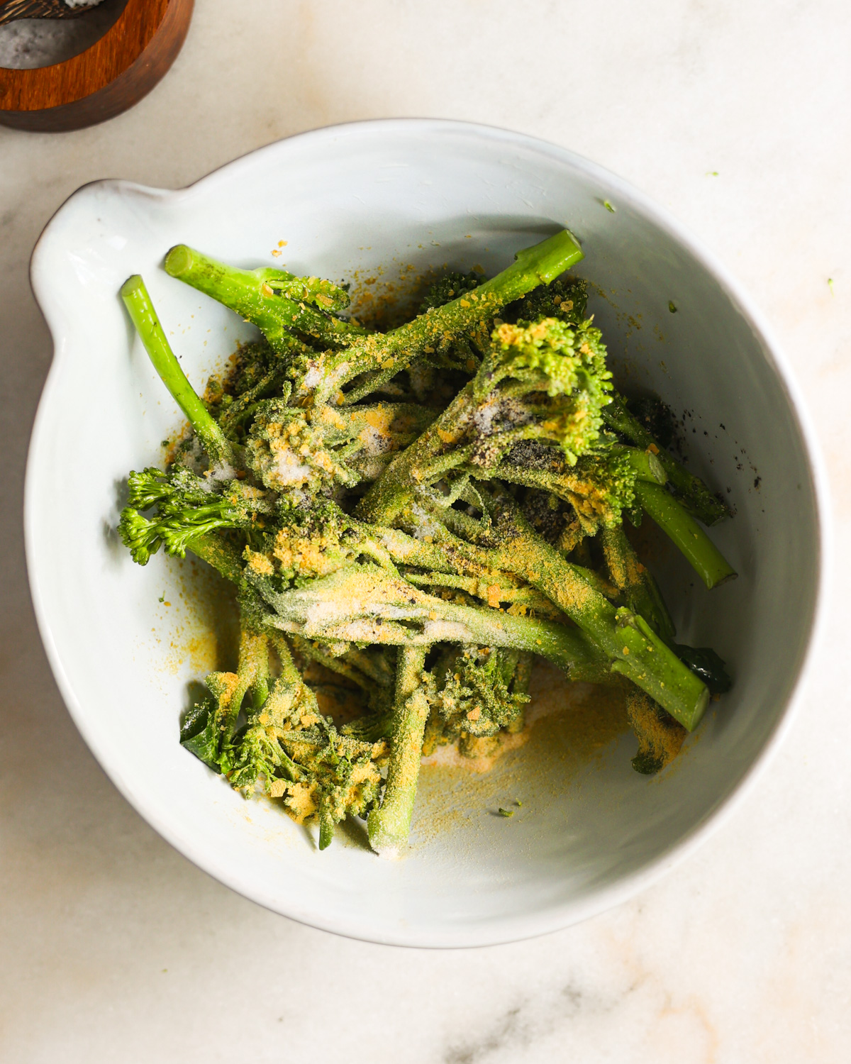 An overhead shot of the broccolini seasoned with the seasonings and nutritional yeast.