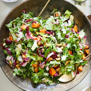 An overhead shot of a large bowl of tossed autumn kale salad.