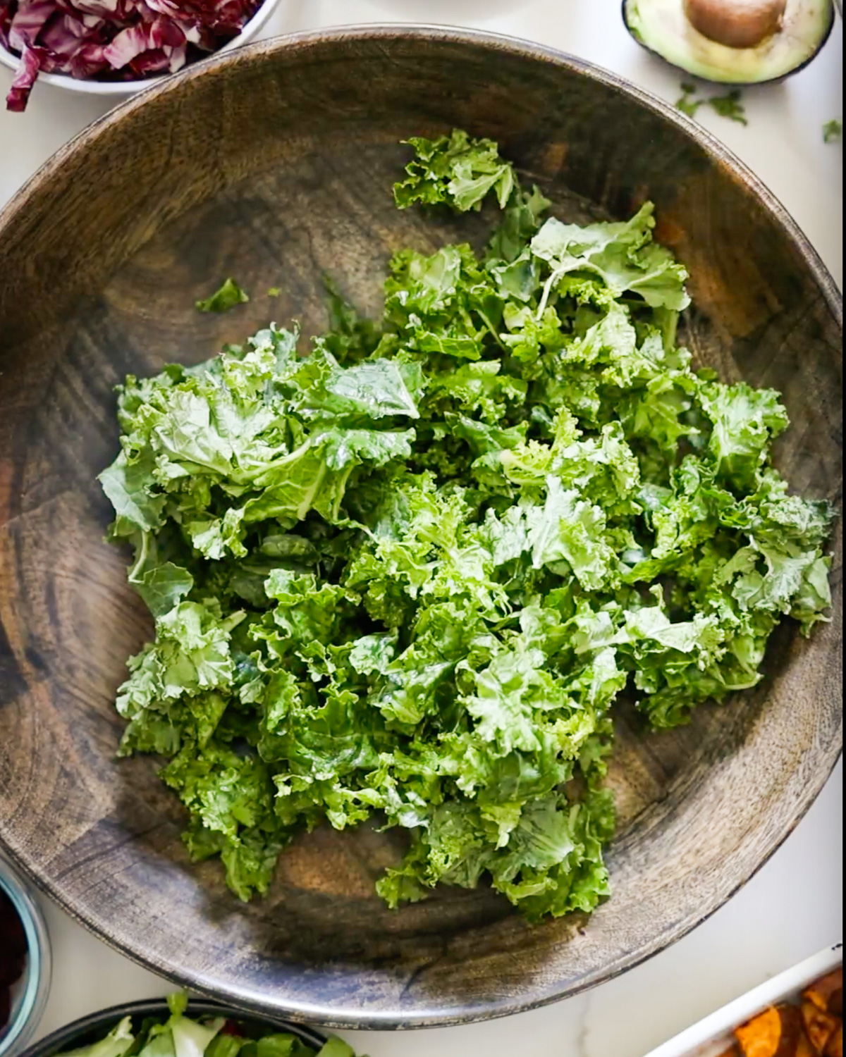 An overhead shot of kale in a wooden mixing bowl.