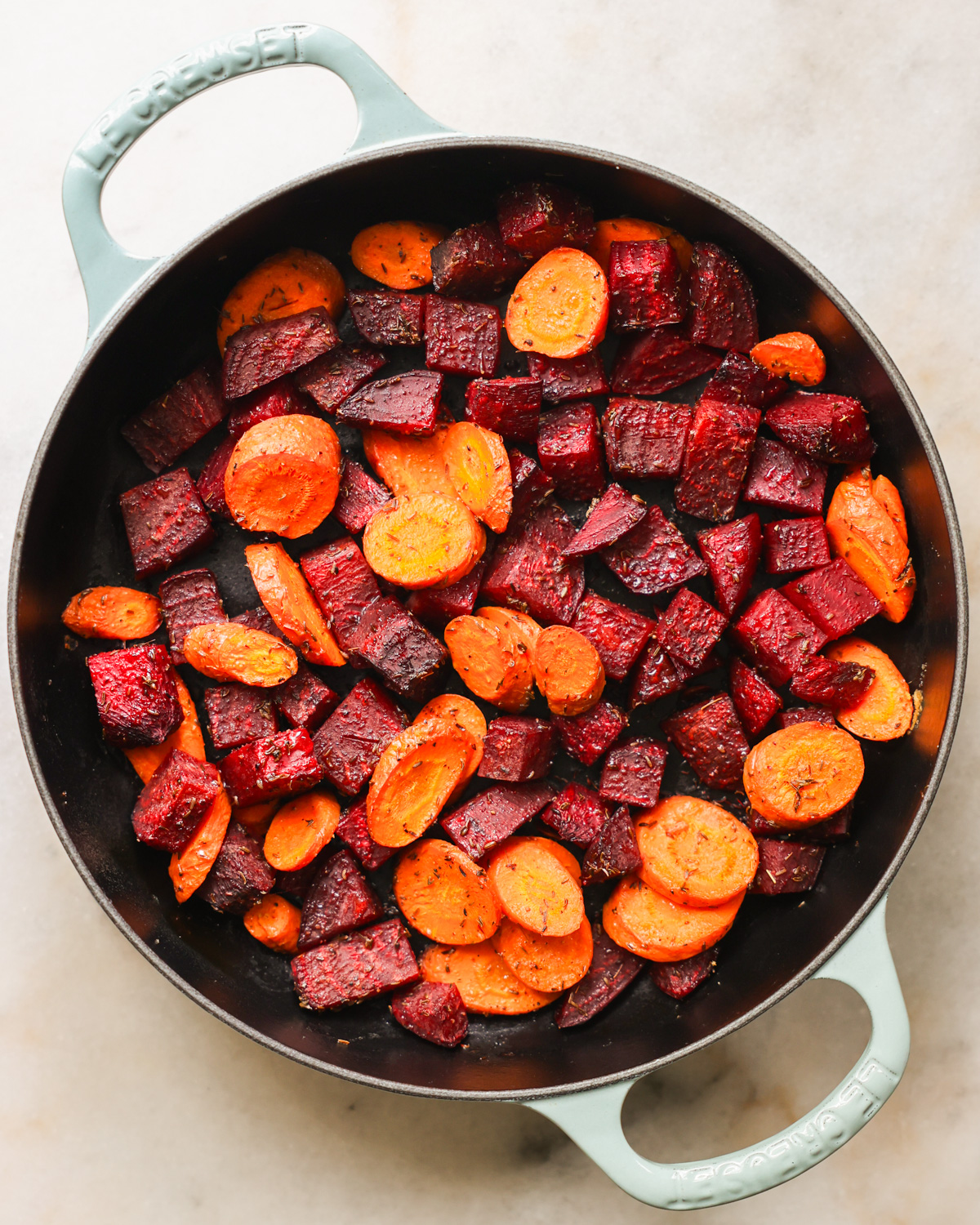 An overhead shot of the roasted beets and carrots in a white pan.