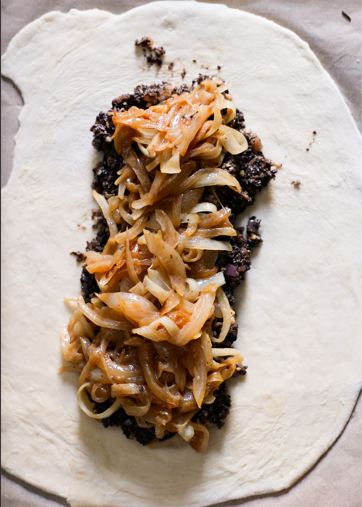 Layering the caramelized onions and mushroom mixture on the rolled out pastry.