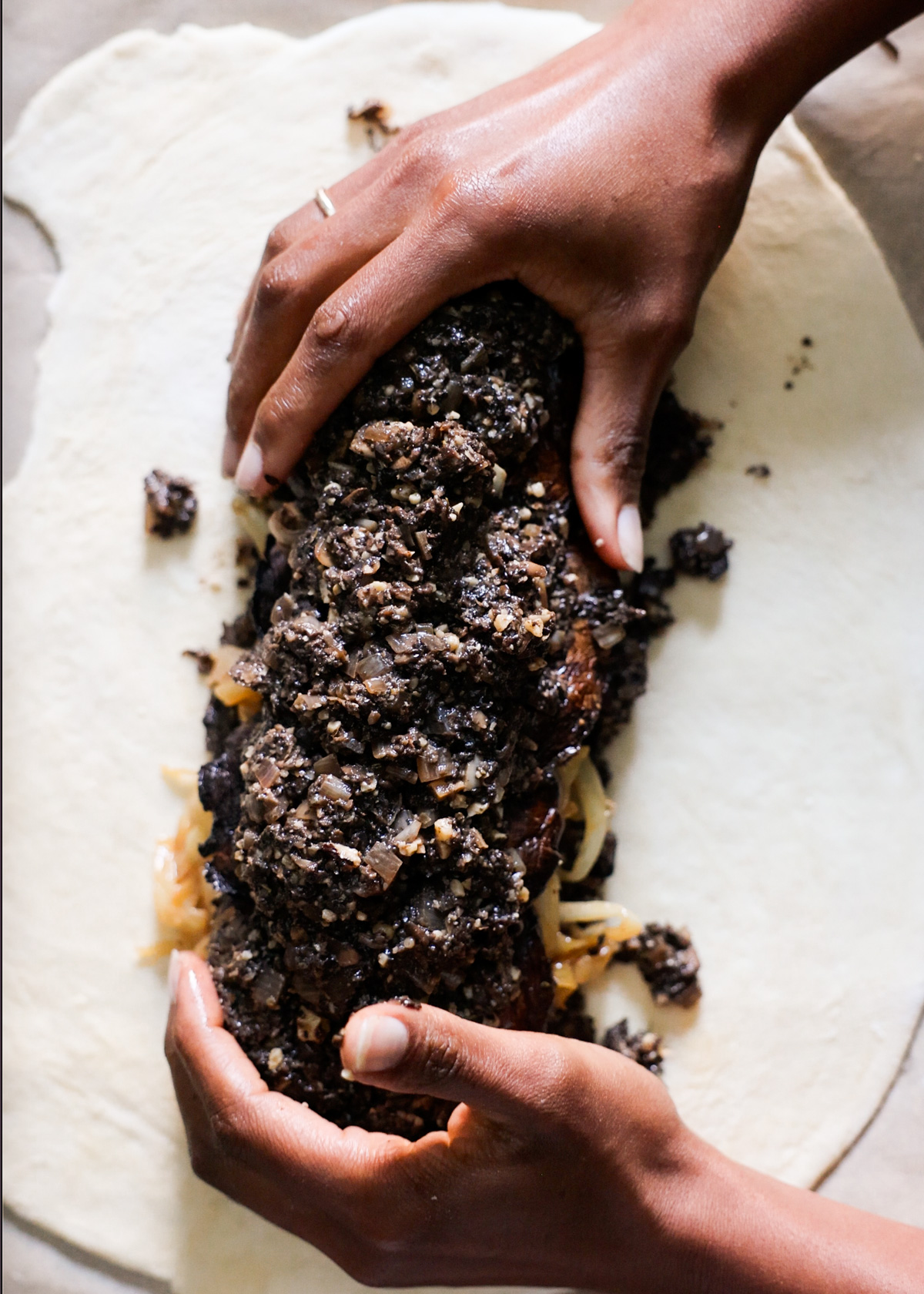 Two brown hands ently forming the vegetable fillings into a compact loaf shape.