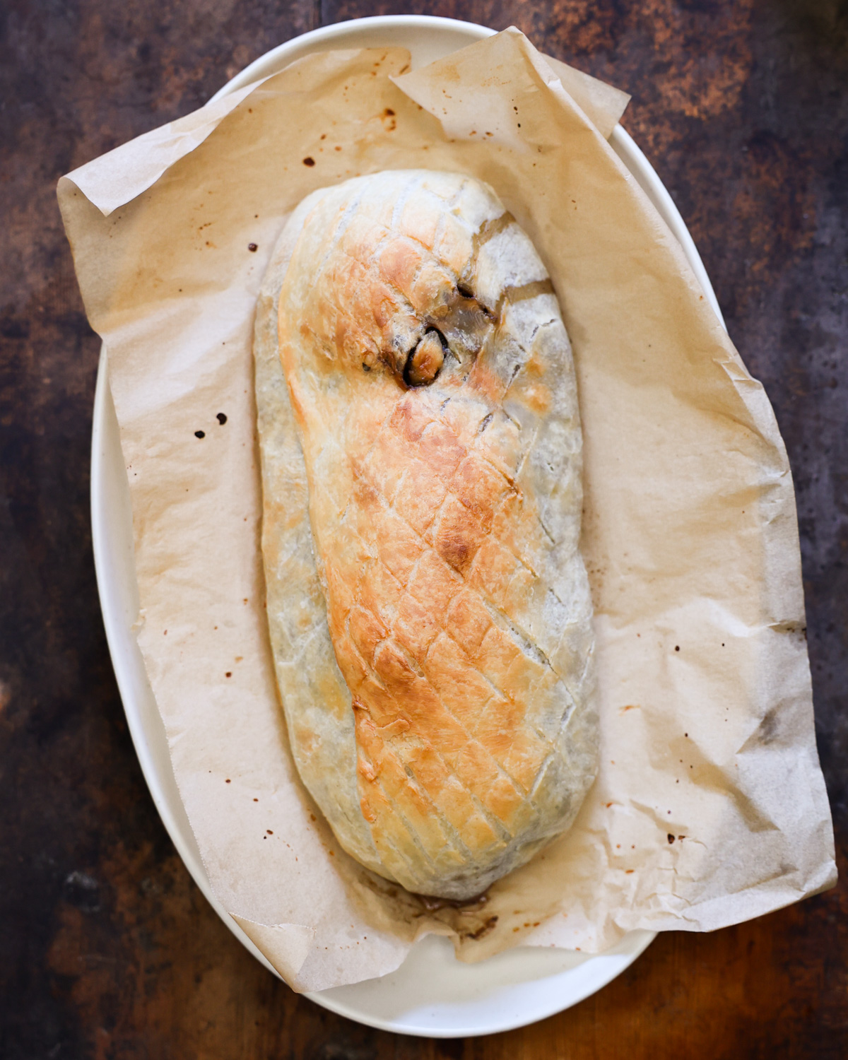 An overhead shot of the baked Wellington on a parchment-lined serving platter.