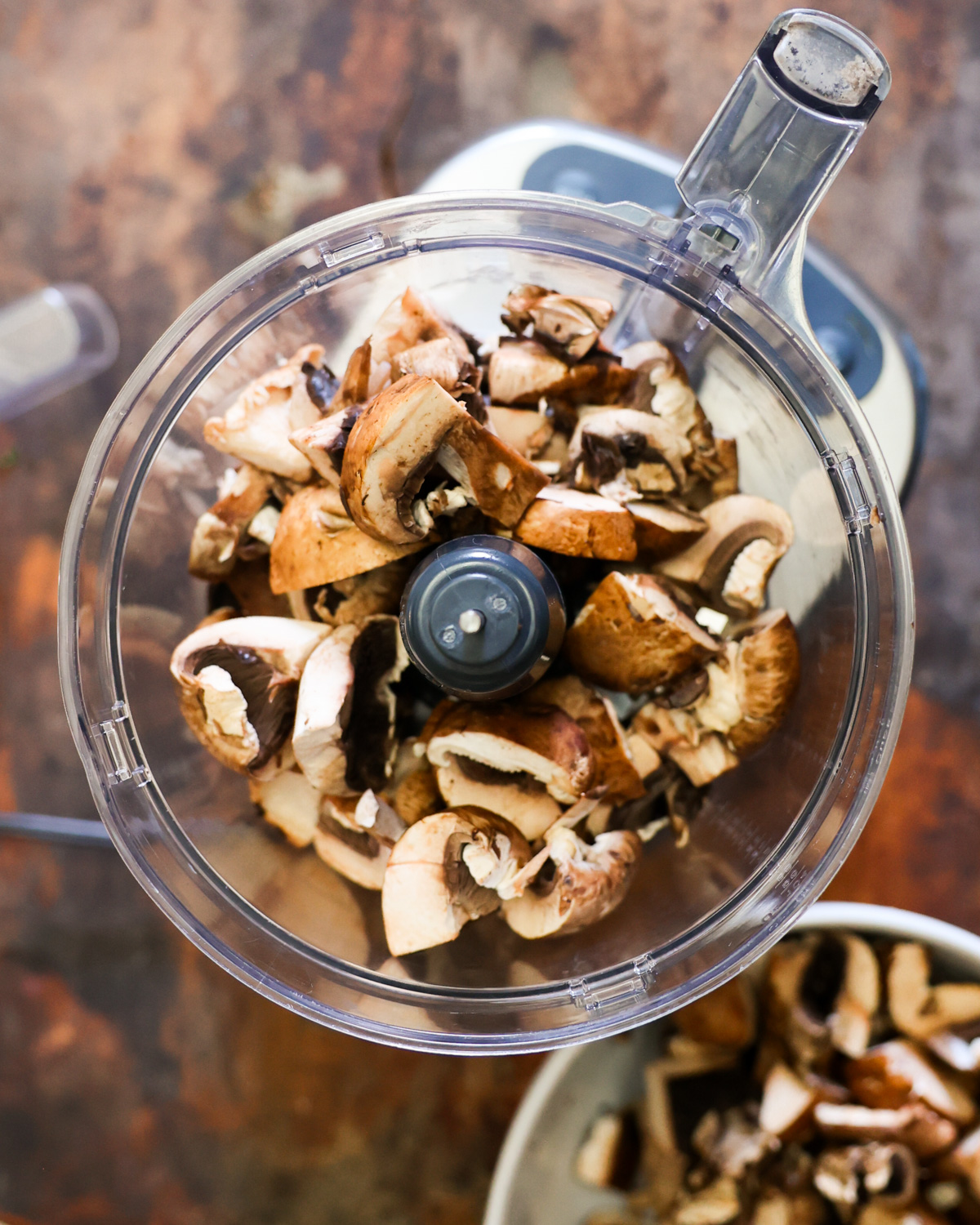 An overhead shot of mushrooms in a food processor.