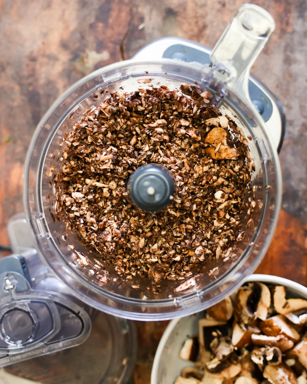 An overhead shot of chopped mushrooms in a food processor.