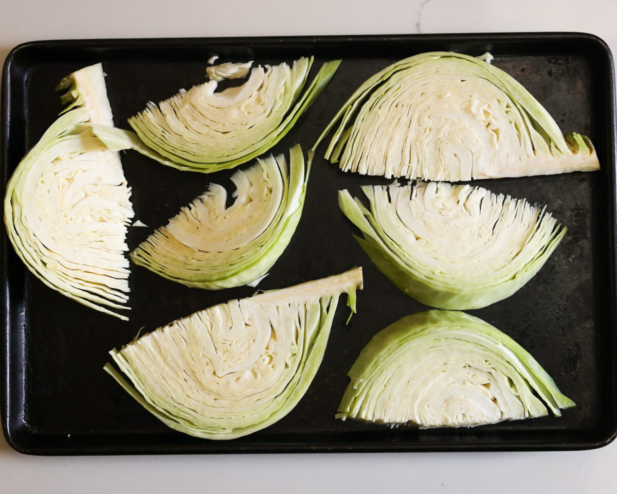 Raw cabbage wedges on baking sheet.