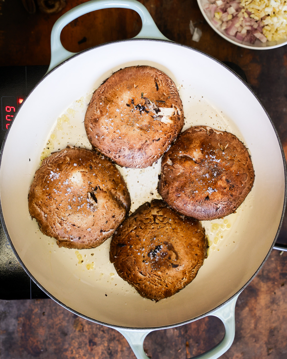 An overhead shot of the portobello mushroom caps cooking in a pan.