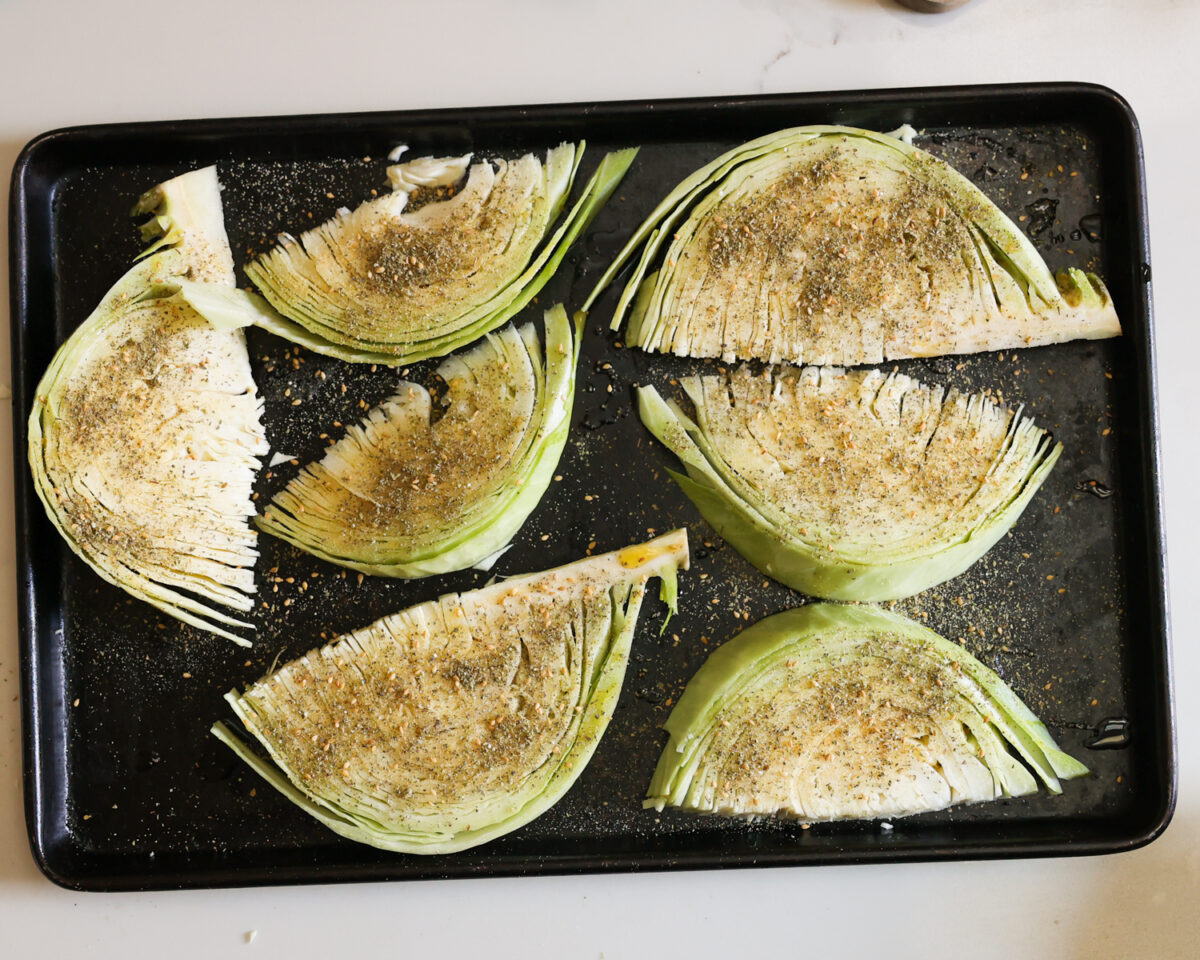 Seasoned cabbage wedges on a baking tray.