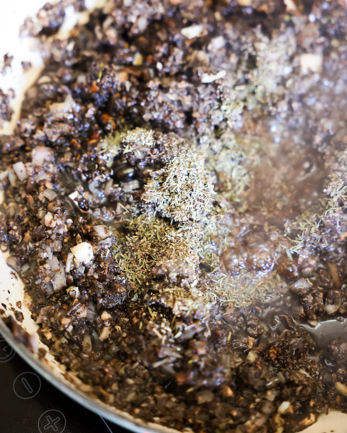 A close-up shot of the chopped onions cooking in a pan with herbs.