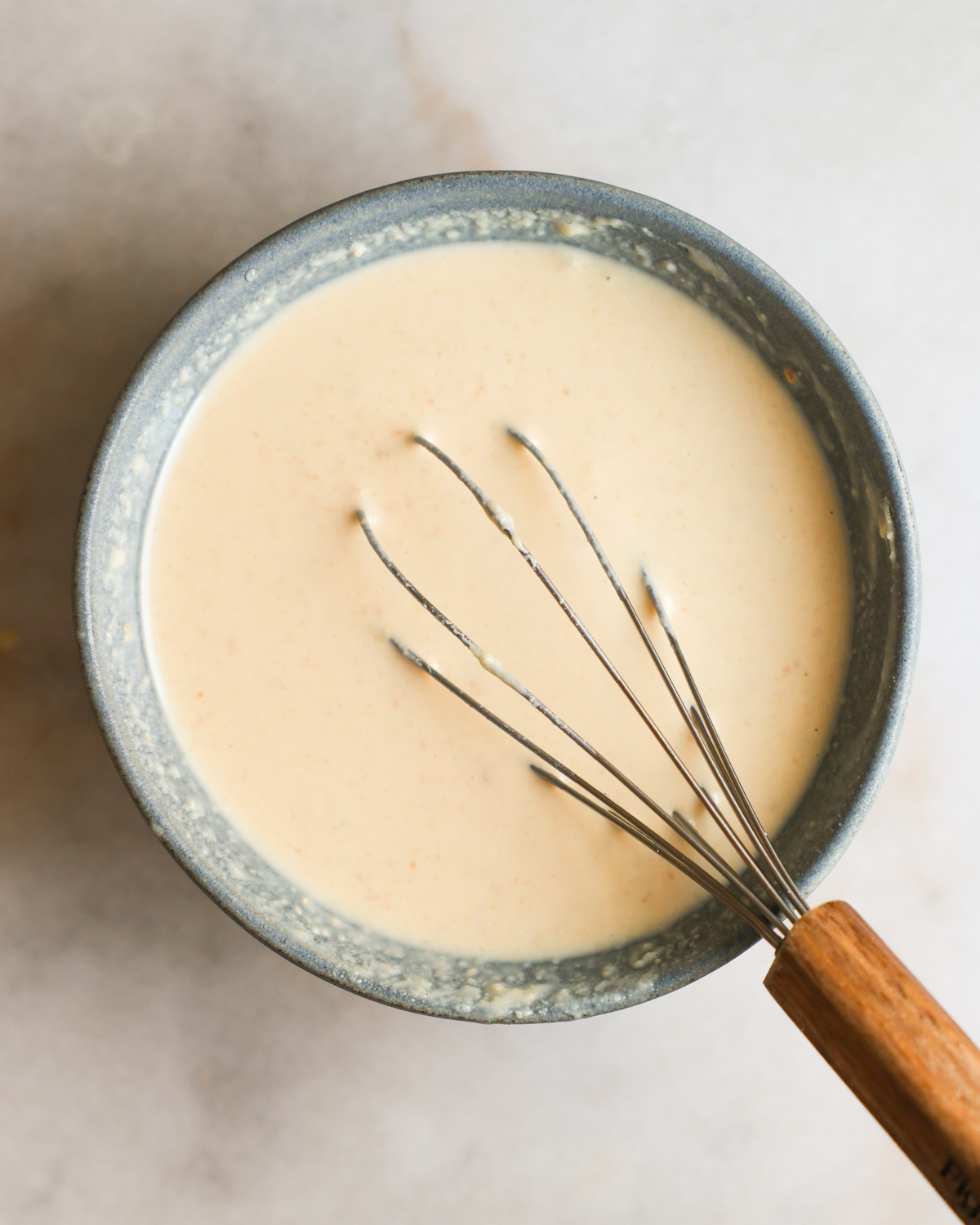 overhead of whisking creamy tahini dressing