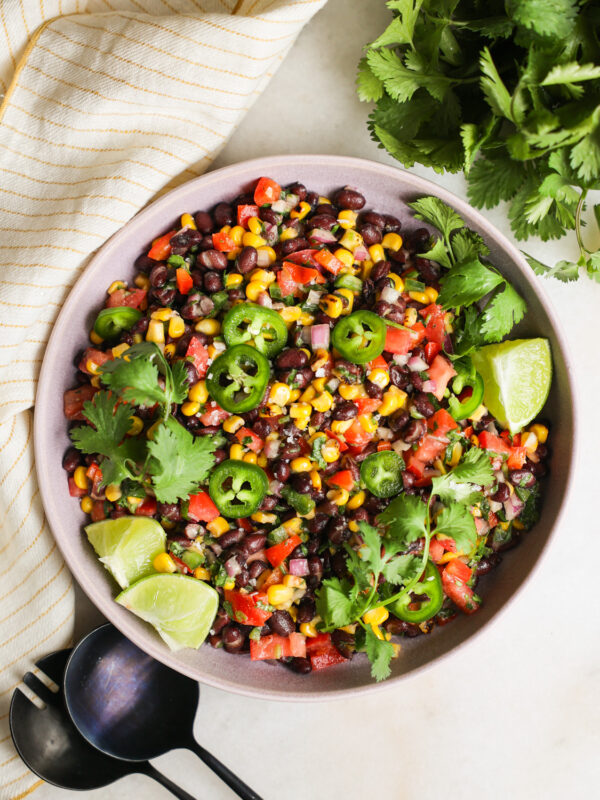 An overhead shot of a bowl of black bean and corn salad with lime, cilantro, and jalapenos.