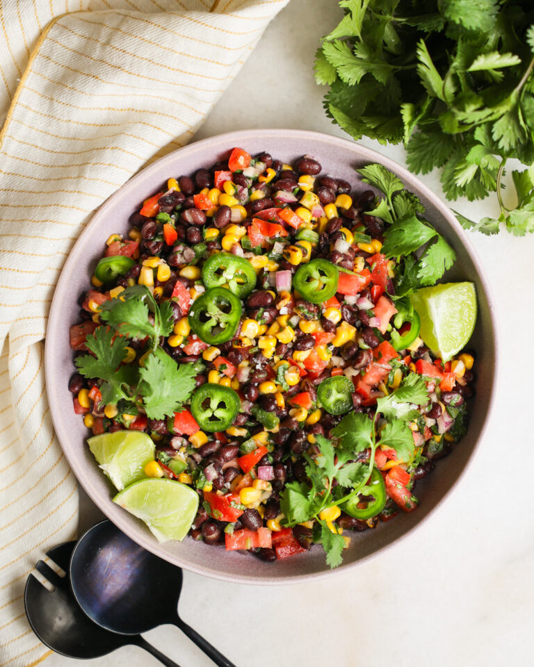 An overhead shot of a bowl of black bean and corn salad with lime, cilantro, and jalapenos.