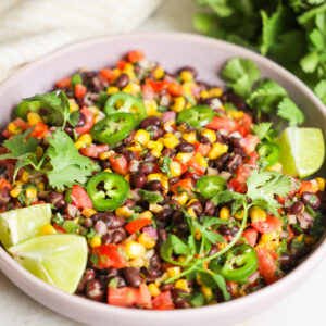A close-up angled shot of a bowl of the black bean and corn salad with cilantro, jalapenos, and lime.