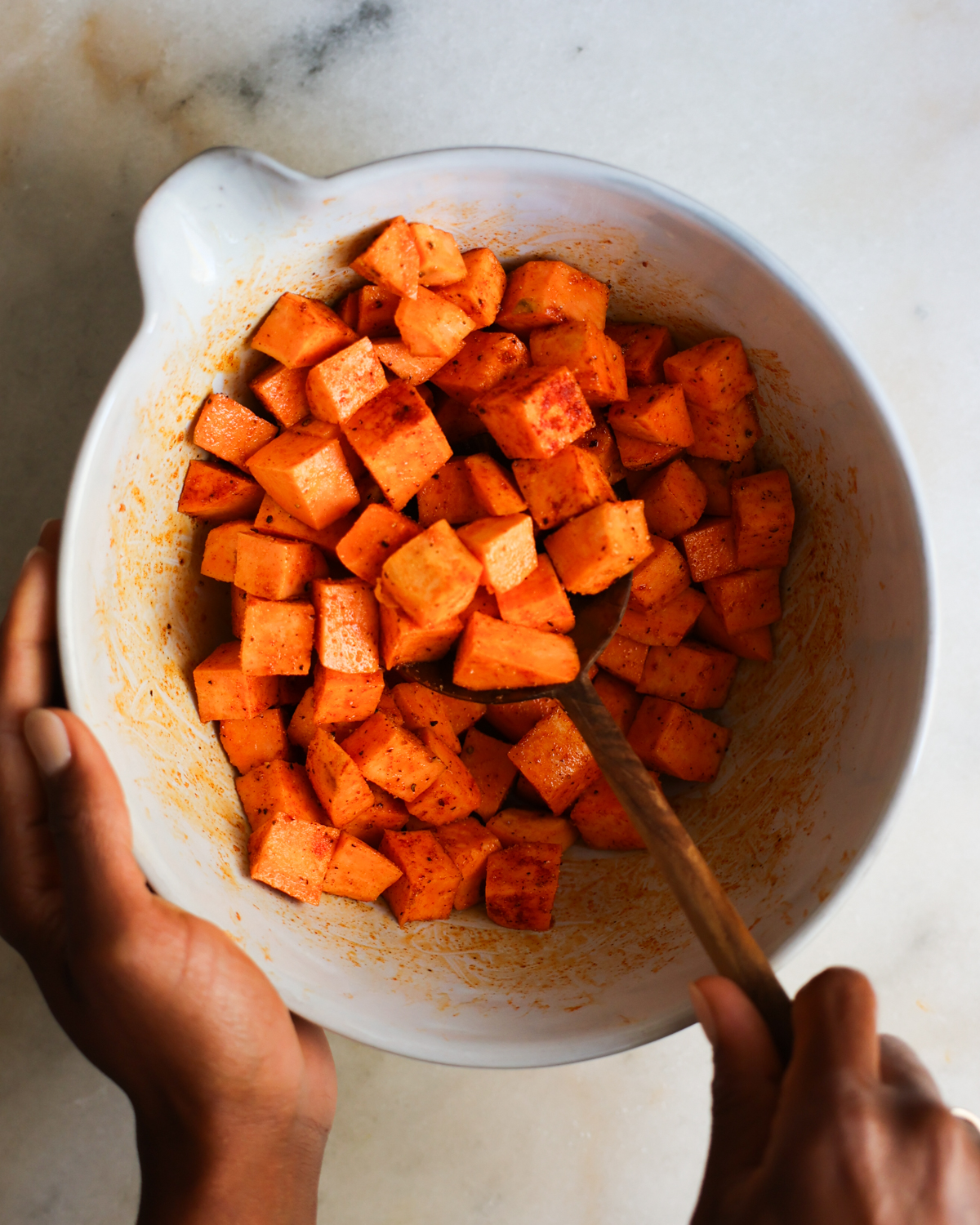 overhead tossing sweet potatoes in spices