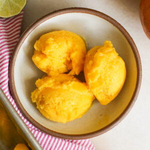 overhead of mango sorbet scoops in a bowl