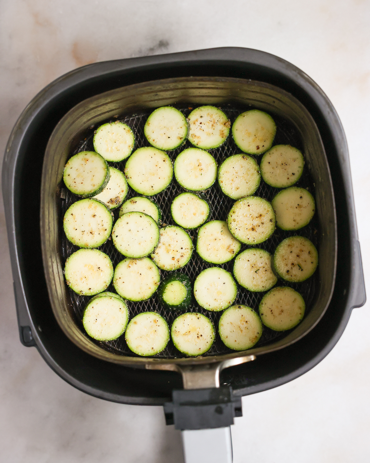 Sliced zucchini in an air fryer basket.