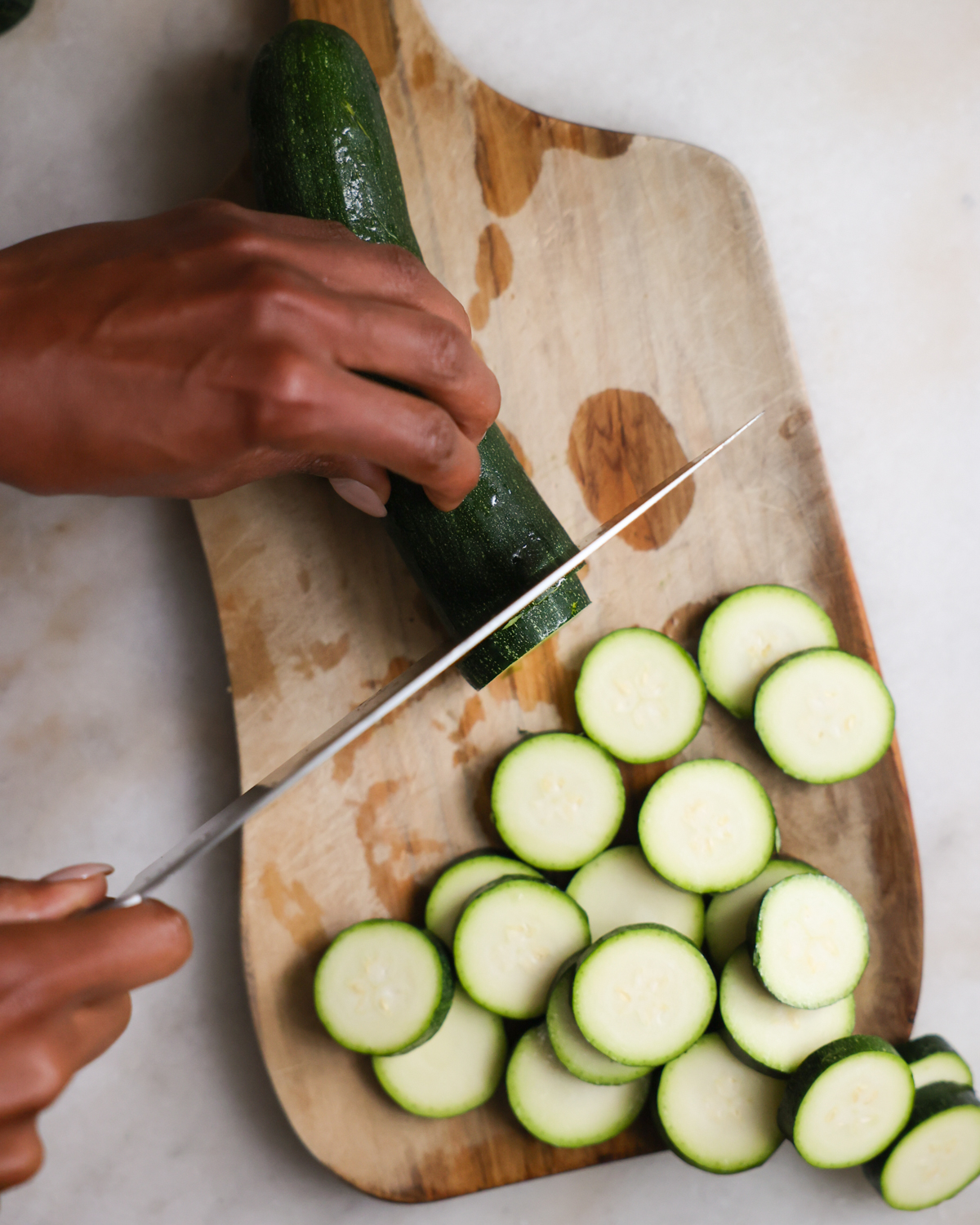 Slicing a zucchini on a cutting board.
