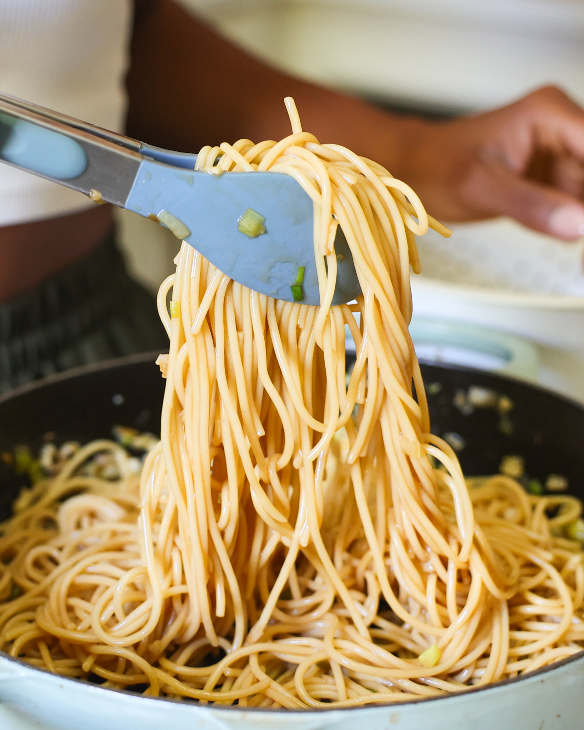 tossing noodles in sauce