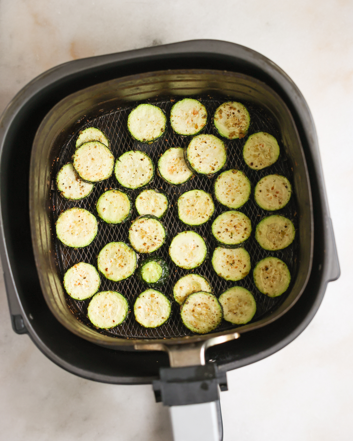 An overhead shot of cooked air fryer zucchini in an air fryer basket.
