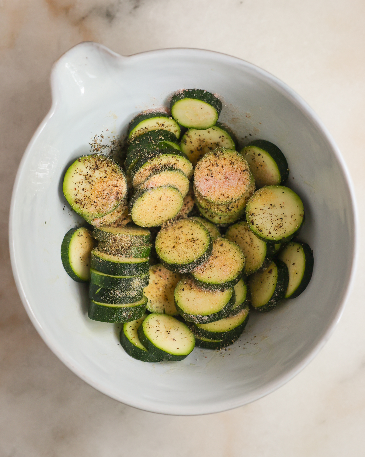 A bowl of zucchini sprinkled with seasonings.