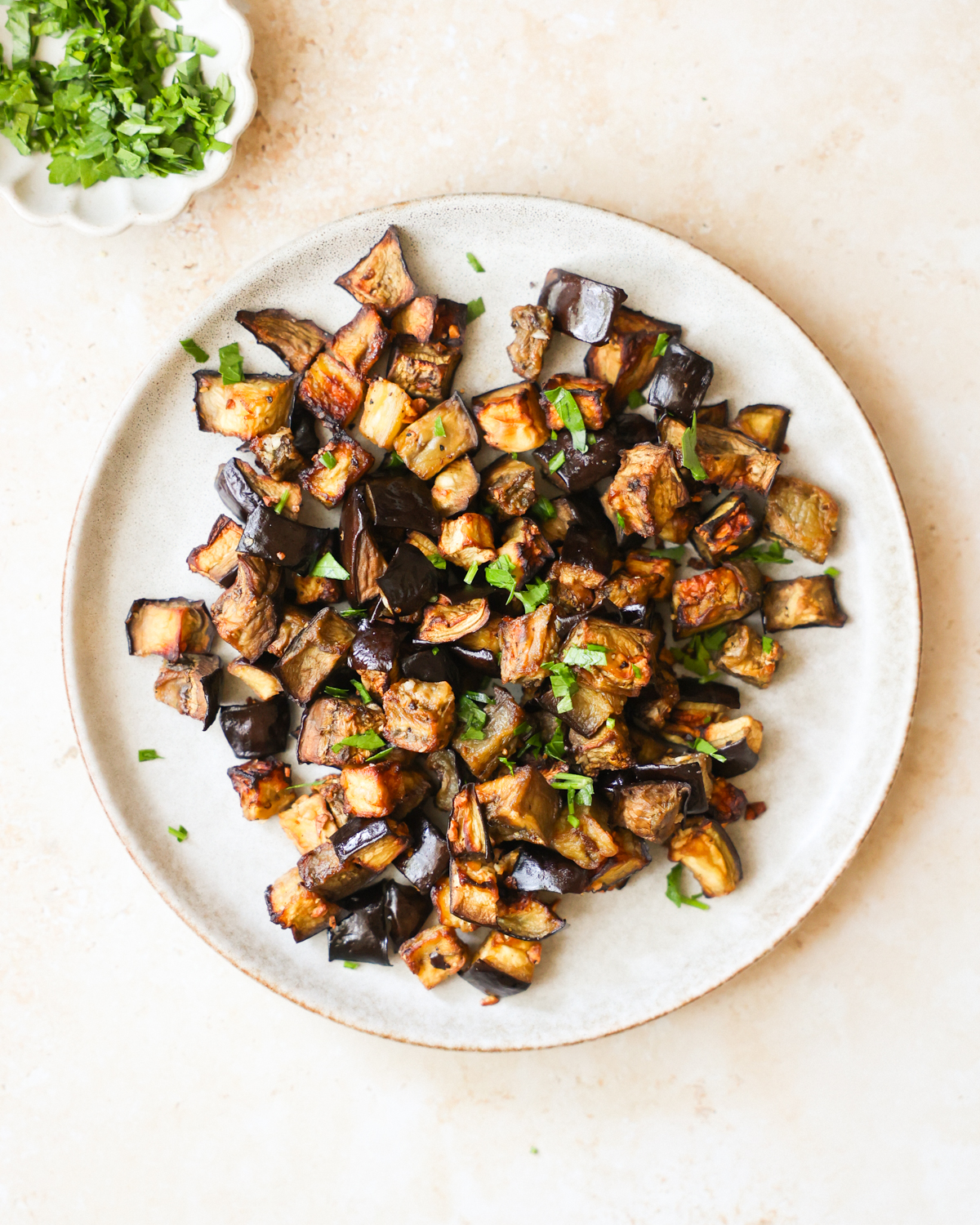 An overhead shot of a plate of air fryer eggplant with chopped herbs.
