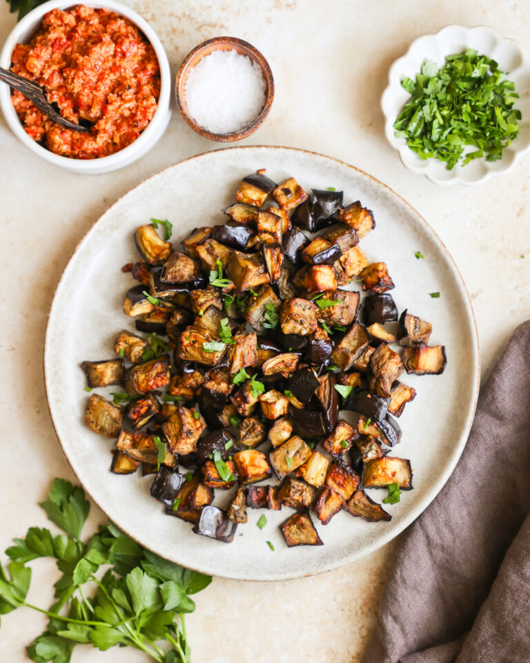 An overhead shot of a serving plate of air fryer eggplant next to small dishes of seasonings.