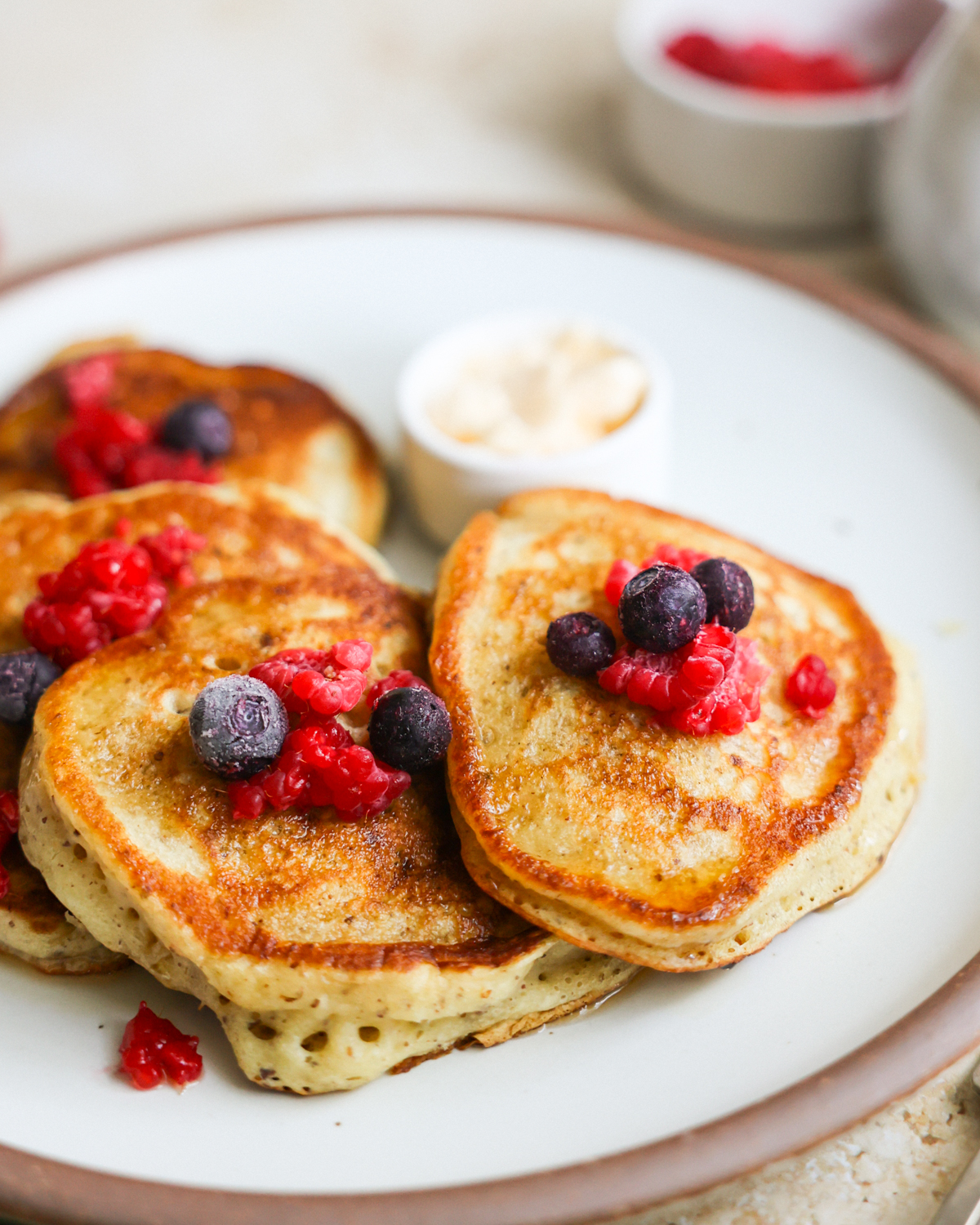 A close-up shot of sourdough discard pancakes on a plate with berries on top.