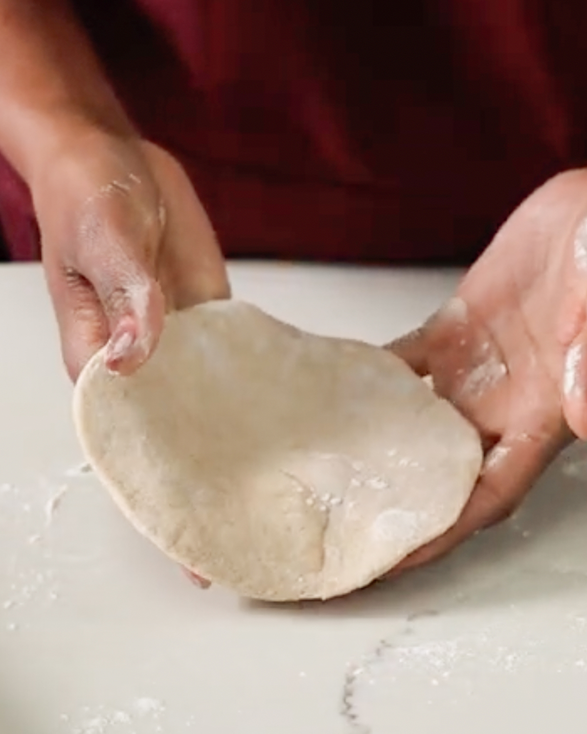 flattened naan dough in hands